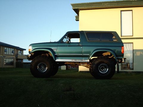 1996 Ford Bronco - This lifted 1996 Ford Bronco is shown in profile against a building and clear sky.