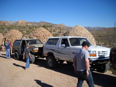 1996 Ford Bronco - Two Ford Broncos are parked on a dirt road in a desert landscape with unique rock formations.