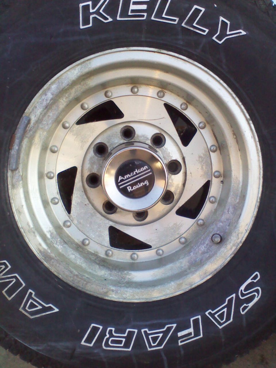 Aluminum alloy wheel with American Racing center cap and Kelly Safari tire. White lettering on tire is partially visible