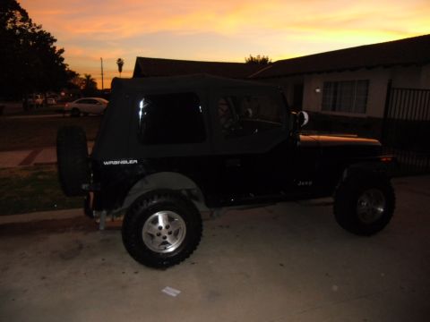 1992 Jeep Wrangler - A black Jeep Wrangler is parked in a driveway with a colorful sunset in the background.