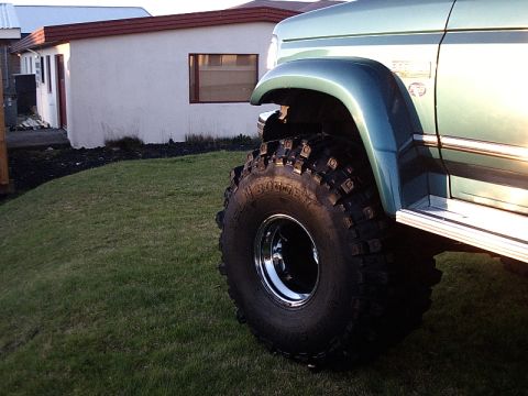 1996 Ford Bronco - A green 1996 Ford Bronco is shown with its front wheel and fender, modified with large off-road tires.