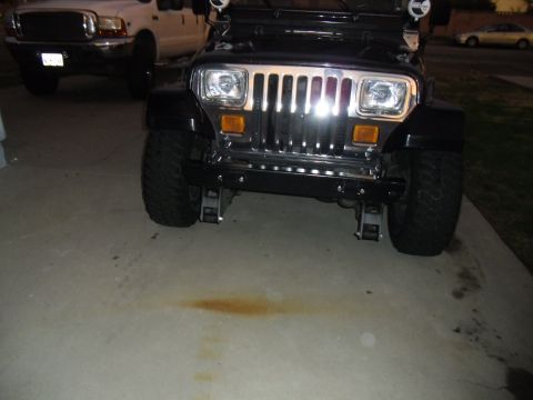 1992 Jeep Wrangler - Front view of a black 1992 Jeep Wrangler with chrome grille and large tires, parked on a concrete driveway.