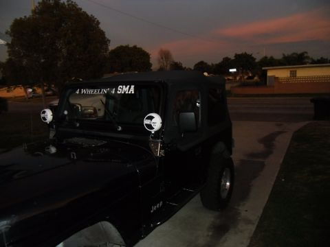 1992 Jeep Wrangler - 1992 Jeep Wrangler parked outside at dusk, showing its front 3/4 view with custom decals and lights.