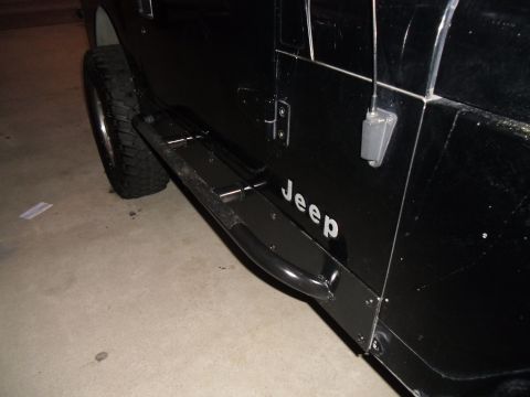 1992 Jeep Wrangler - Close-up of the side of a black Jeep, showing the door, side step, and tire.