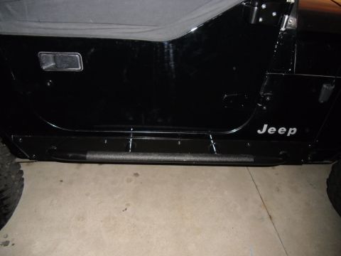 1992 Jeep Wrangler - Side view of a black Jeep Wrangler showing the door, side step, and part of the soft top.
