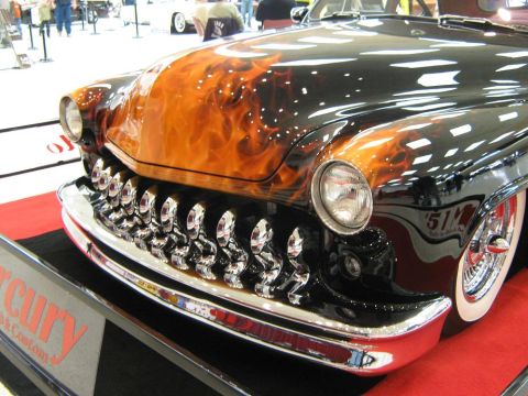 2000 Mercury Grand Marquis - A classic hot rod with a distinctive grille and flame paint job is displayed at a car show.