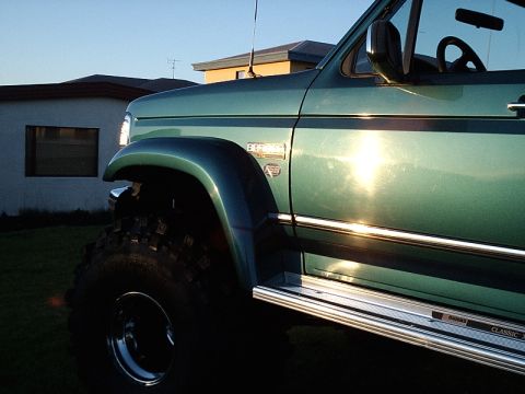 1996 Ford Bronco - Side view of a green 1996 Ford Bronco, chrome trim and prominent off-road tires.