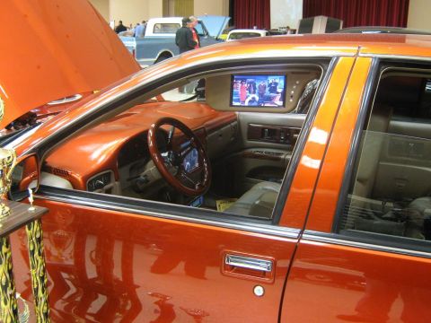 2000 Mercury Grand Marquis - The interior of a customized orange car is visible, complete with a mounted television screen.