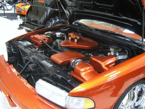 2000 Mercury Grand Marquis - Customized engine bay features bright orange accents and a miniature truck on the air intake cover. Another vehicle is visible in the backg…