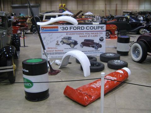 2000 Mercury Grand Marquis - A display at a car show features a model kit for a 1930 Ford Coupe, surrounded by car parts and other vehicles in the background.