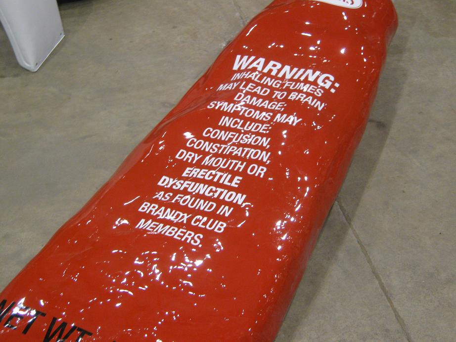 Red tube with white warning text about inhaling fumes, on a concrete floor