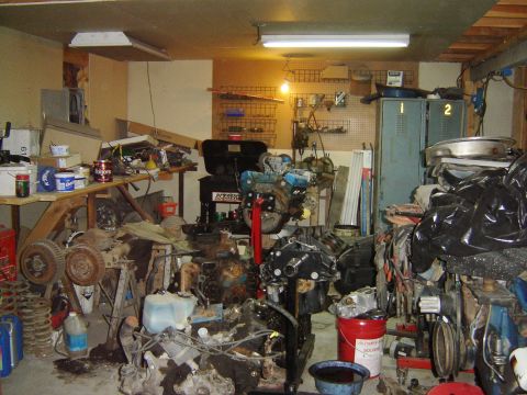 1984 Ford Mustang - A messy garage filled with various car engines and spare parts, suggesting ongoing or past repair work.