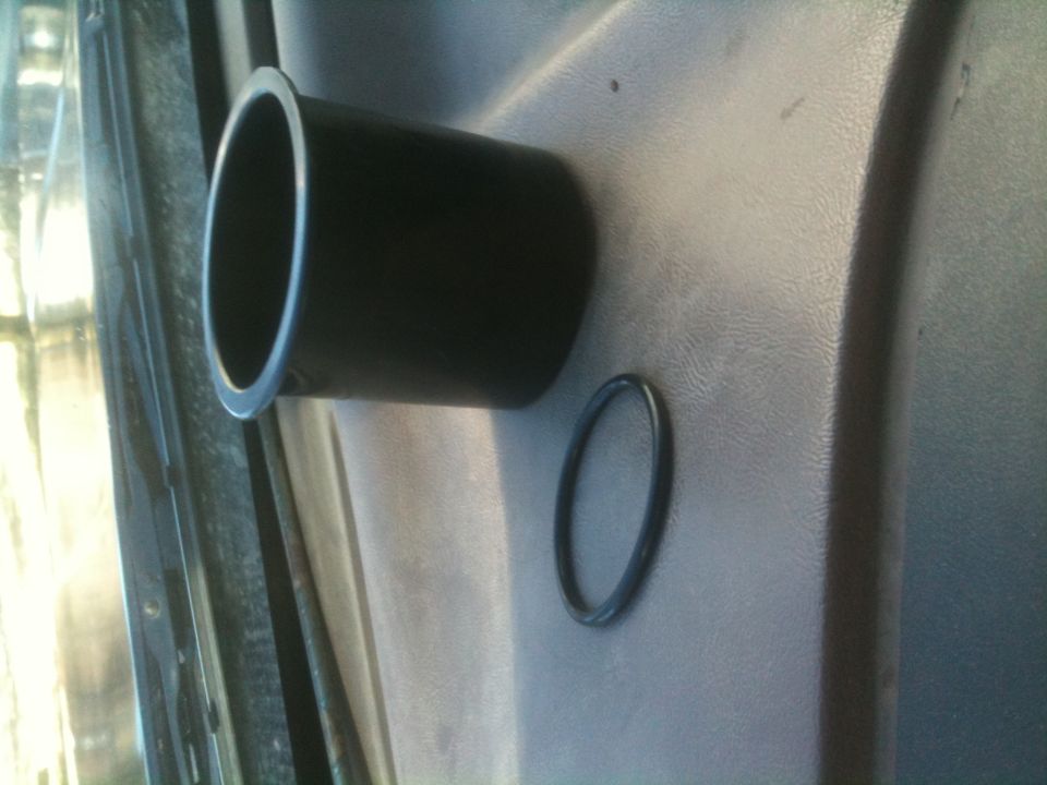 Interior door panel with black cup holder and a black o-ring on the textured surface. Supermotors.net logo visible