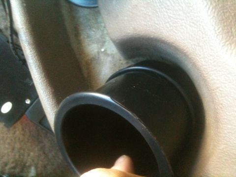 1993 Ford Bronco - A hand is visible near the opening of a dark, circular cup holder mounted in the vehicle's interior.
