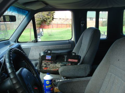 1989 Ford F-250 - The interior of a truck cab is shown, a toolbox and a bottle of brake fluid.