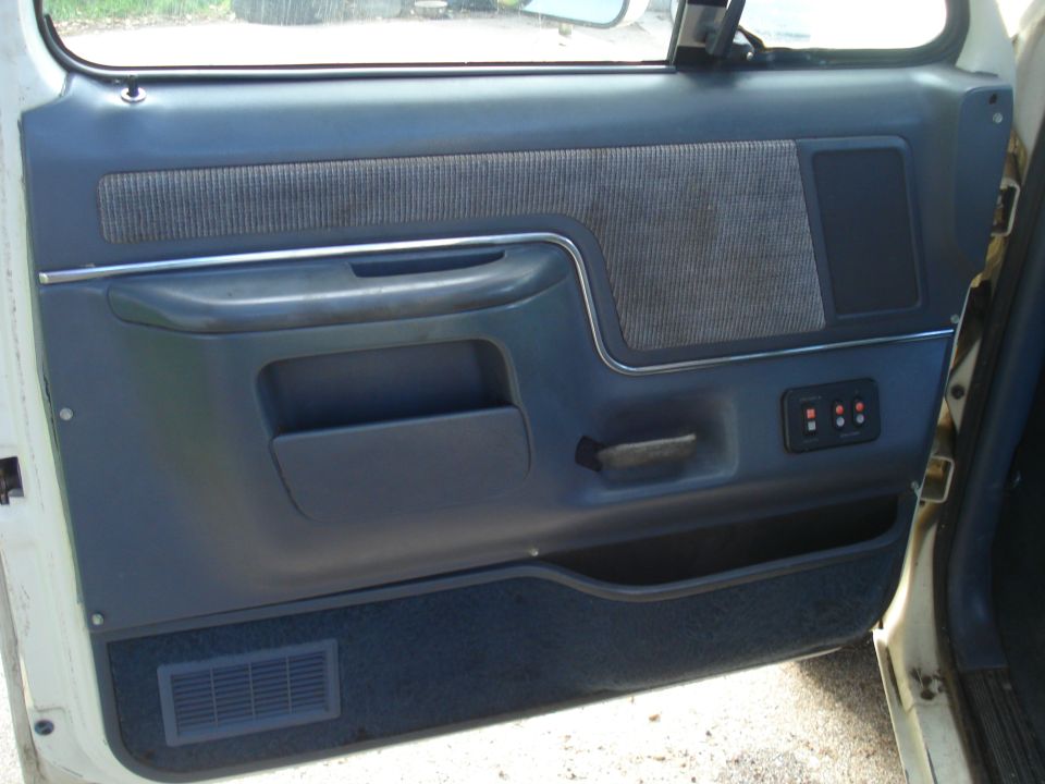 Blue interior door panel of a truck with cloth insert and window switches