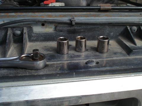 1989 Ford F-250 - A socket wrench and three sockets are laid out on a dark surface, suggesting a repair or maintenance task.