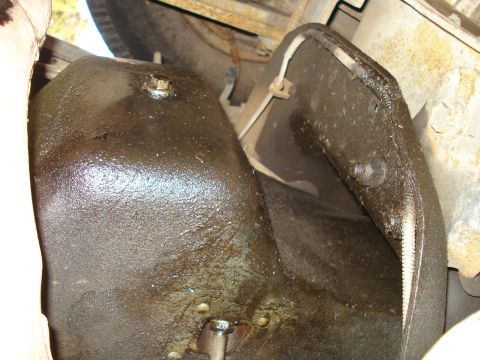 1989 Ford F-250 - Close-up view of the greasy underside of a vehicle, focusing on the oil pan and surrounding components.