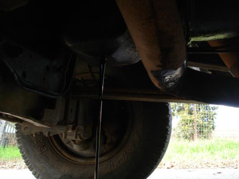 1989 Ford F-250 - Oil is draining from the oil pan of a vehicle. The underside and a tire are visible.