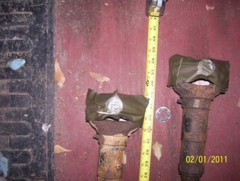 1978 Ford Bronco - Two rusty metal shafts are shown with a tape measure for scale, indicating their length.