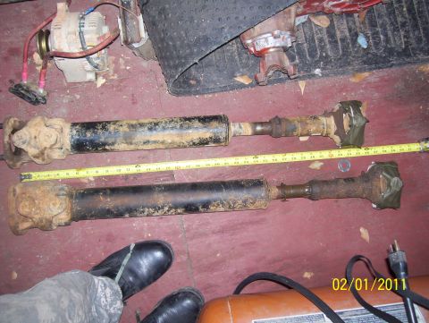 1978 Ford Bronco - Two driveshafts are laid out and measured with a yellow tape measure. Other parts and a date stamp are visible in the background.