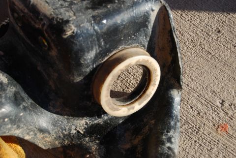 1982 Ford Bronco - A rubber bushing is visible on a dirty black metal component, with a concrete surface in the background.