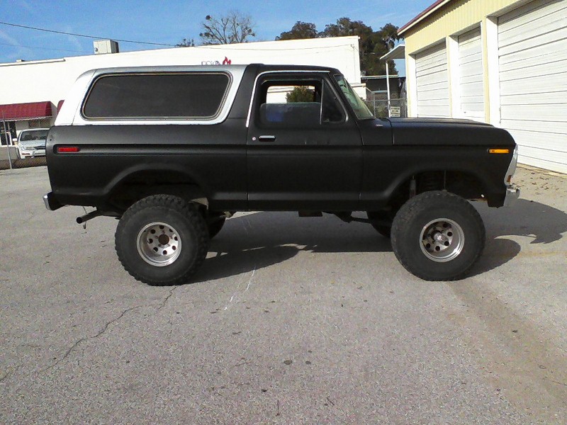 Side view of a black lifted SUV with a white removable hardtop