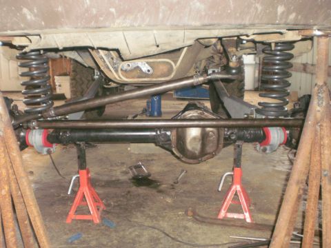 1995 Ford Bronco - Vehicle's rear axle and suspension parts are elevated on jack stands for maintenance.