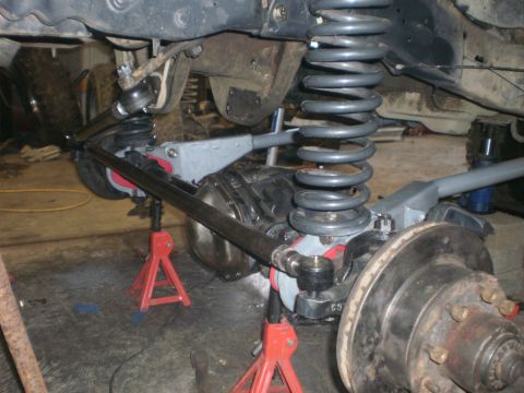 1995 Ford Bronco - The front suspension and steering components of a vehicle are visible, supported by red jack stands.