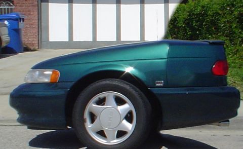 1993 Ford Taurus - This green sedan is parked in front of a garage door with a blue trash can nearby.