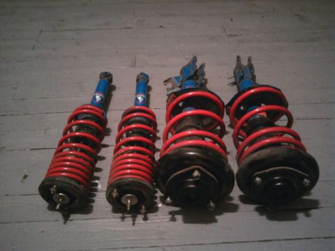 1978 Ford Bronco - Set of four shock absorbers, likely for a vehicle, displayed on a wooden surface.