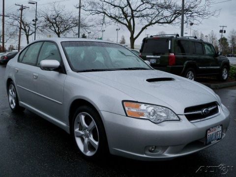 2006 Subaru Legacy - A silver Subaru sedan is parked on a wet asphalt lot with a dark SUV in the background.
