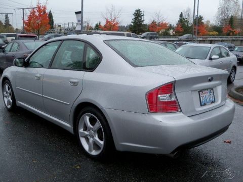2006 Subaru Legacy - Rear view of a silver 2006 Subaru Legacy sedan parked in a lot on a rainy day. Other vehicles and autumn trees are visible in the backgroun…