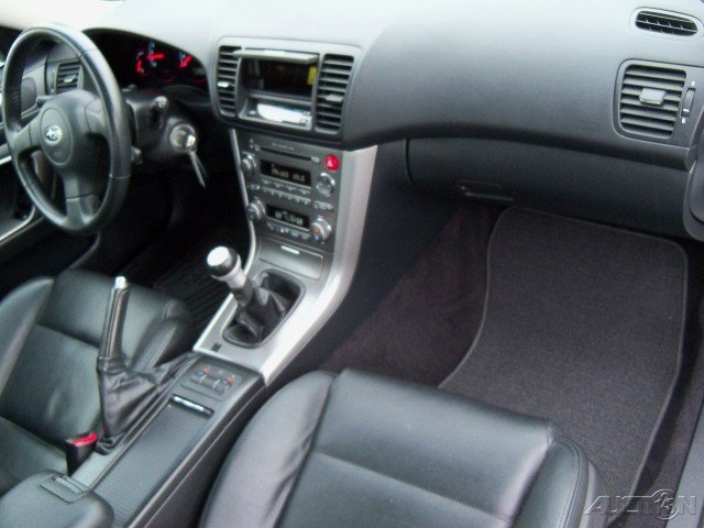 Black leather car interior with a manual transmission, dashboard, and floor mats