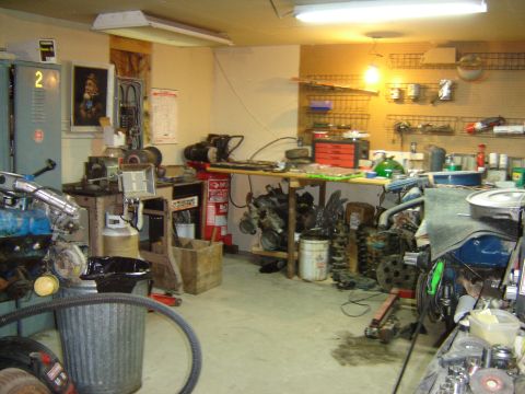 1984 Ford Mustang - A cluttered garage filled with automotive parts and equipment, suggesting a workshop environment.