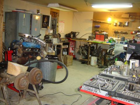 1984 Ford Mustang - A cluttered garage scene displays an engine, tools, and spare parts, suggesting ongoing automotive work.