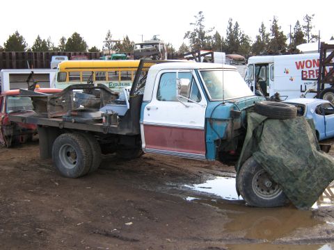 1972 Ford F-250 - A disassembled Ford F-series truck sits in a muddy junkyard with other vehicles in the background.