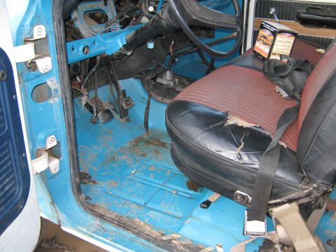 1972 Ford F-250 - The interior of a 1972 Ford F-250 shows a worn seat and blue painted floor, with some boxes on the seat.