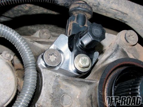 1990 Ford Bronco - Tight underside detail of a wheel-speed sensor mounted to a cast steering knuckle or axle housing with a bare machined bracket, secured by…
