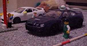 2006 Ford E350 - A Lego scene with two toy cars and figures, set up on a carpeted surface.