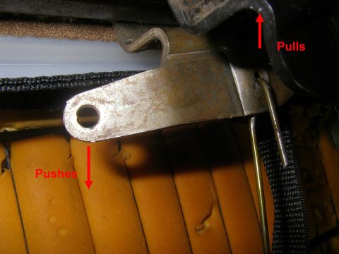 1990 Ford Bronco - Close-up of a seat mechanism, showing the interaction of metal parts and foam padding, with directional arrows indicating operation.
