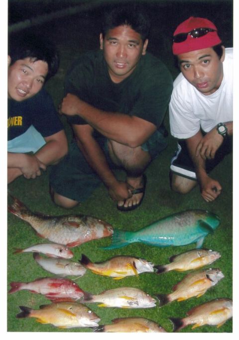 1991 Ford Bronco - Three men kneel on grass at night behind a laid-out catch of reef fish including a teal-green parrotfish and several yellow and red snapper…