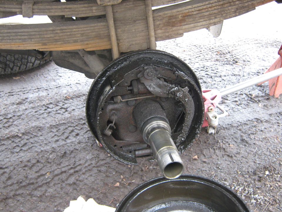 close-up of a dirty truck brake drum assembly with leaf springs above