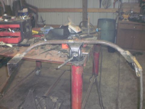 1995 Ford Bronco - A metal crossmember is secured in a vise, surrounded by various tools and workshop equipment.