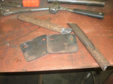 1995 Ford Bronco - Metal parts and tools are laid out on a wooden surface, suggesting a repair or fabrication project.
