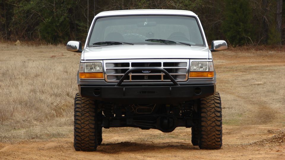 White 1995 Ford Bronco front view with aftermarket bumper and large tires