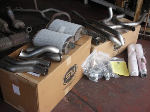 2004 Ford Crown Victoria - Various exhaust system components are laid out on cardboard boxes in a workshop.