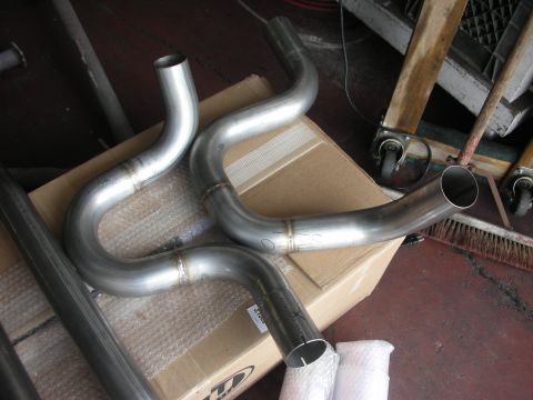 2004 Ford Crown Victoria - Stainless steel exhaust headers are shown on a cardboard box in a workshop setting.
