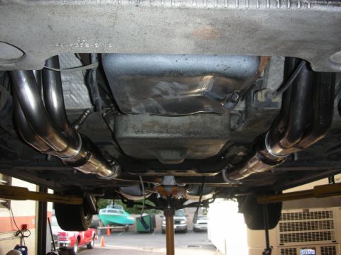 2004 Ford Crown Victoria - Underside of a car raised on a shop lift, looking rearward at freshly installed stainless long-tube headers on both sides feeding into new…