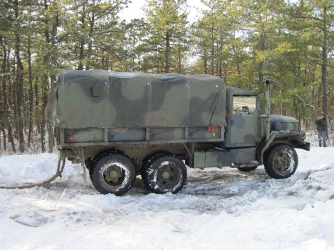 2005 Ford Excursion - A camouflaged military truck is parked in a snowy wooded area.